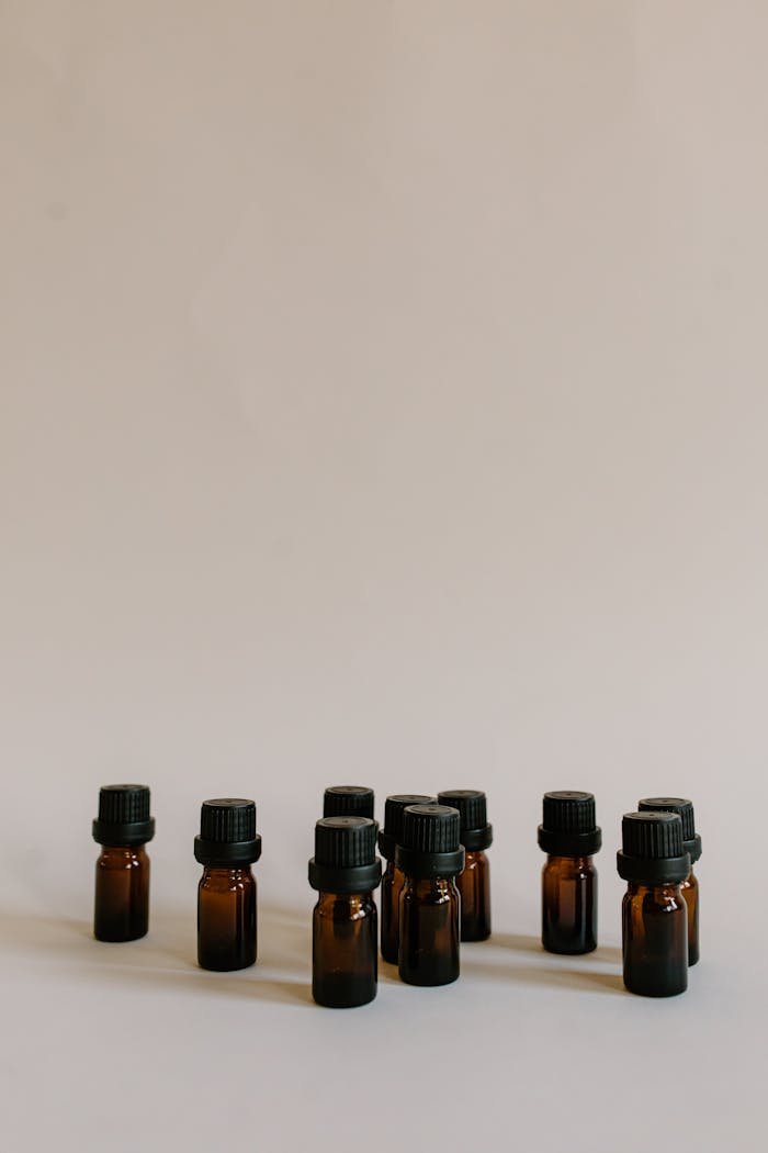 Aesthetic arrangement of brown essential oil bottles against a plain background with ample copy space.