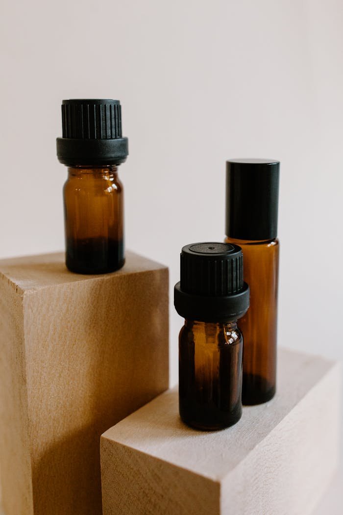 Minimalist still life with brown glass essential oil bottles on wooden blocks, perfect for aromatherapy concepts.