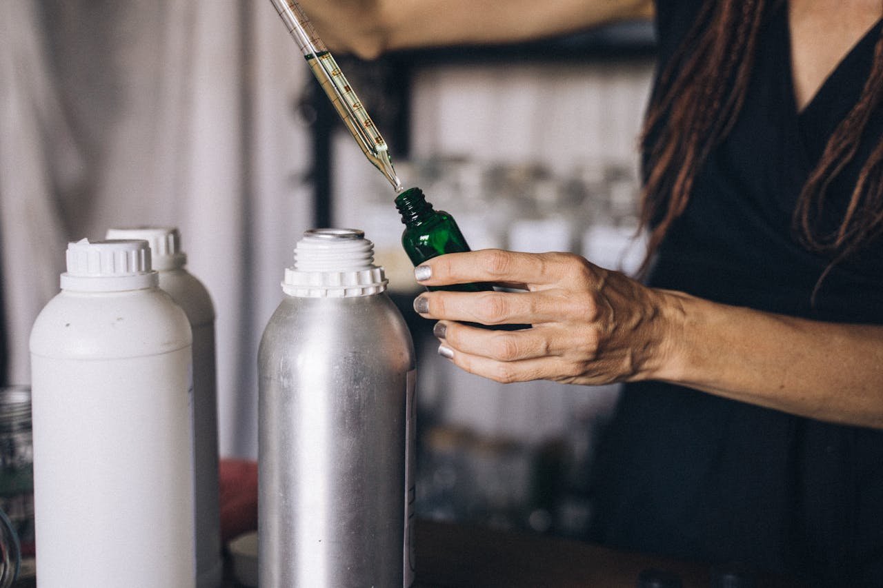 Woman using a dropper to prepare aromatherapy oils in an indoor setting.