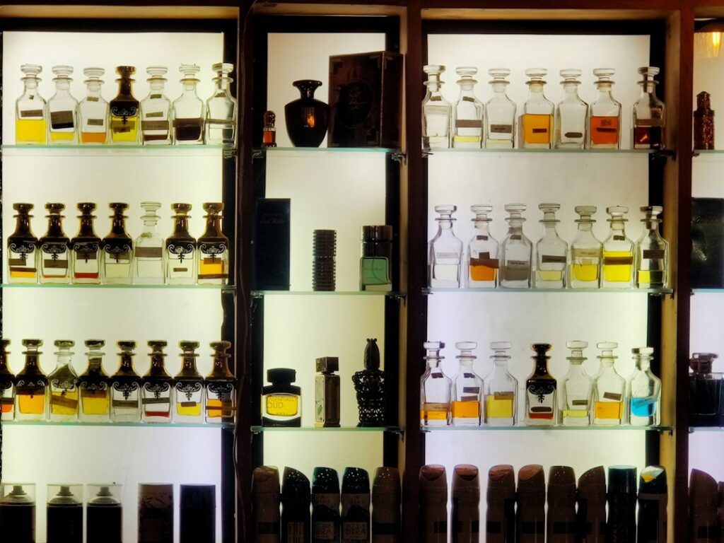What Is Attar? History, How It’s Made and How to Wear It Rows of glass attar and perfume bottles on a wooden shelf