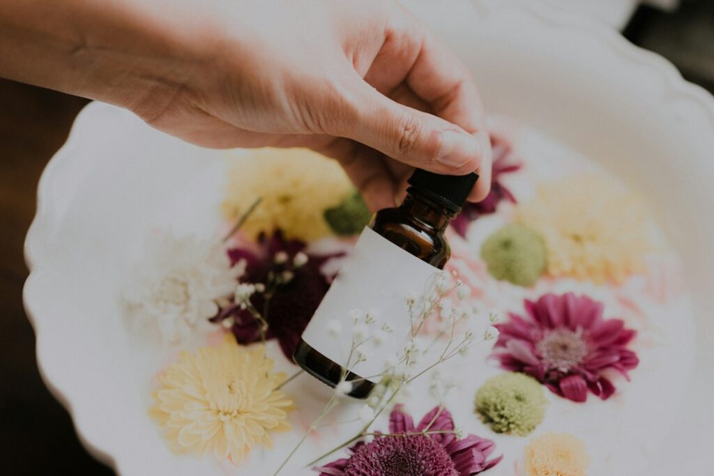 Hand holding a small essential oil bottle among plants
