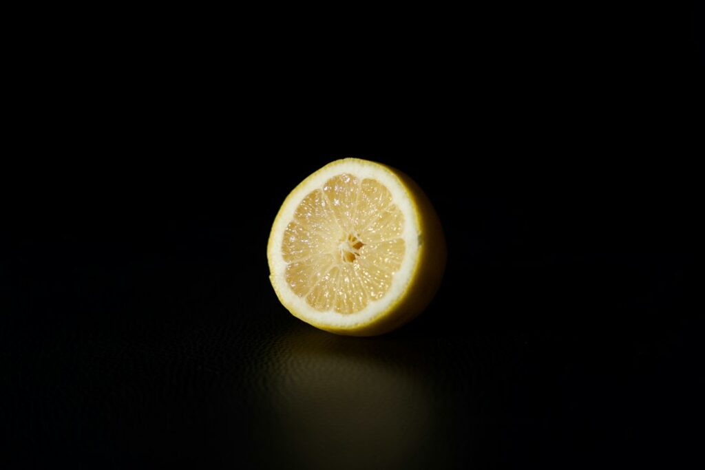 A fresh lemon on a plain background, representing the citrus top notes of fresh men's perfume oils